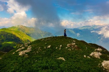 Kafkasya dağlarında güzel bir dağ manzarası. Tepenin tepesinde duran bir kadın var.