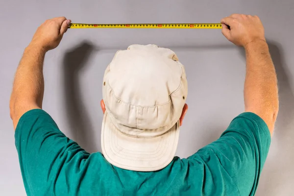 Fröhlicher bärtiger Handwerker im grünen T-Shirt mit Maßband — Stockfoto