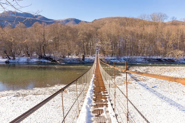 Dağ nehri kış manzarası üzerindeki asma köprü. — Stok fotoğraf