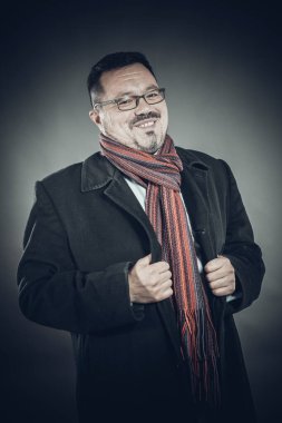 Gözlüklü, ceketli ve mendilli, neşeli bir adam.