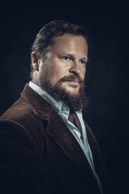 Siyah arka planda takım elbise giymiş şık sakallı bir adam..