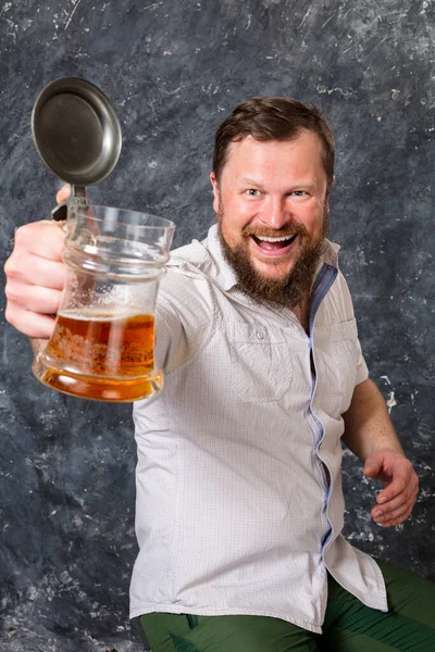 Homem barbudo sorridente em camisola com caneca de cerveja — Fotografia de Stock