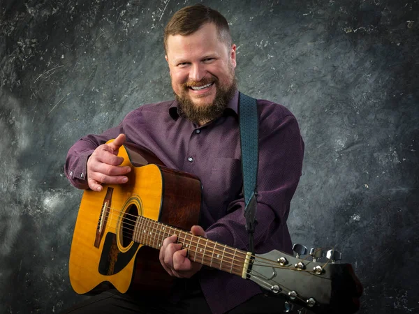 Mature musician plays acoustic guitar emotional studio portrait. — Stock Photo, Image