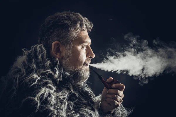 Vollbärtiger Mann im Pelzmantel, der Pfeife raucht — Stockfoto