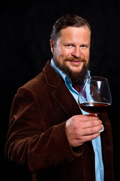 Stylish bearded man dressed in brown jacket with glass of whisky