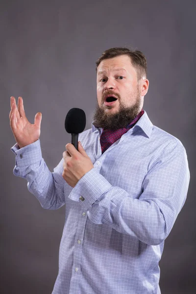 Cantante emotivo barbuto con microfono vestito in camicia ritratto in studio. — Foto Stock