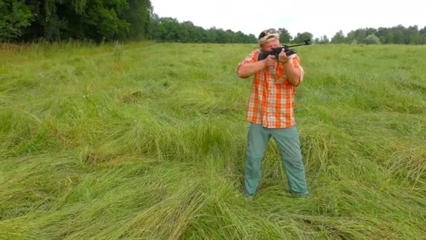 Chasseur au chapeau et lunettes de soleil visant un pistolet — Video