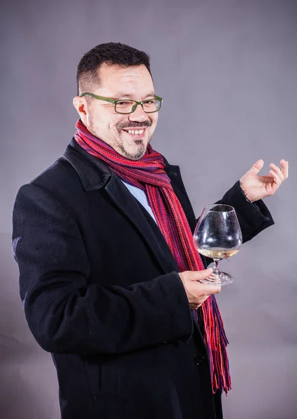 Solido uomo allegro in cappotto e fazzoletto in piedi con vetro di vino — Foto Stock