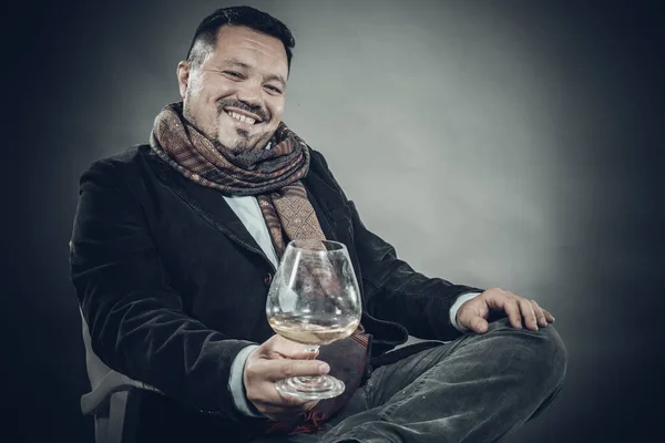 Solido uomo allegro in fazzoletto seduto con bicchiere di vino — Foto Stock