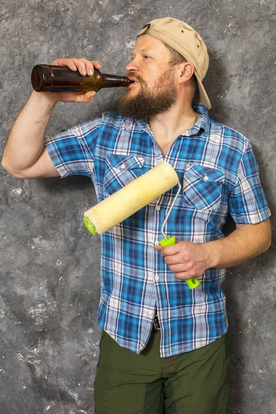 Vreugdevolle bebaarde voorman heeft een pauze met een fles bier — Stockfoto