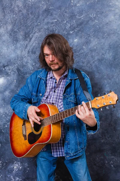 Mature musician plays acoustic guitar studio portrait. — Stock Photo, Image