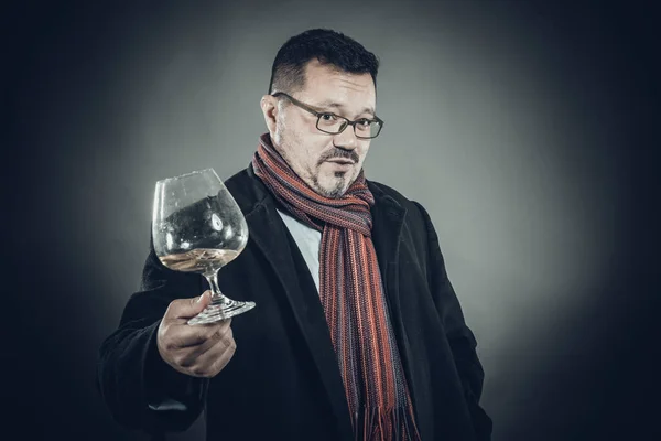 Pevný veselý muž v kabátě a kapesníku, stojící se sklenicí vína — Stock fotografie