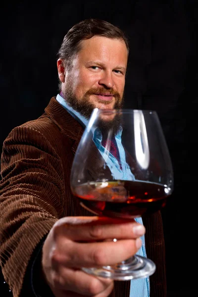Elegante hombre barbudo vestido con chaqueta marrón con vaso de whisky — Foto de Stock