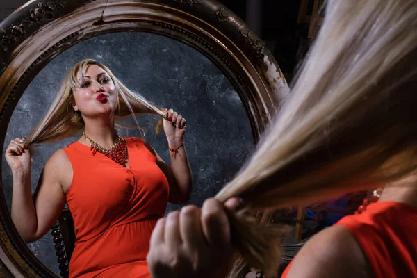 Atractiva mujer regordeta mirando su reflejo en el espejo de estilo retro Fotos De Stock Sin Royalties Gratis