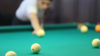 Yeşil masada bilardo oynayan genç bir kadın.