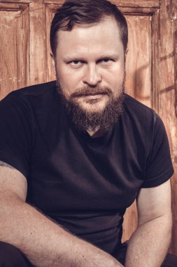 Olgun sakallı adam klasik kapının arkasında oturuyor.