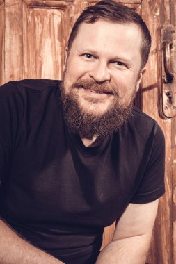 Olgun sakallı adam klasik kapının arkasında oturuyor.