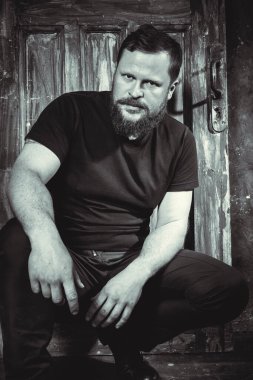 Olgun sakallı adam klasik kapının arkasında oturuyor.