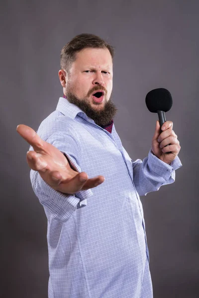 Cantante emotivo barbuto con microfono vestito in camicia ritratto in studio. — Foto Stock
