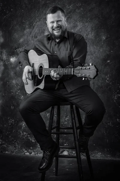 Mature musician plays acoustic guitar emotional studio portrait. — Stock Photo, Image