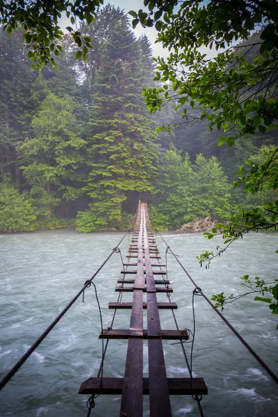 Escena con río de montaña y puente colgante — Foto de Stock