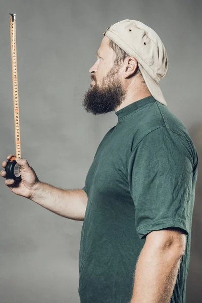 Joyeux artisan barbu en t-shirt vert avec ruban à mesurer — Photo