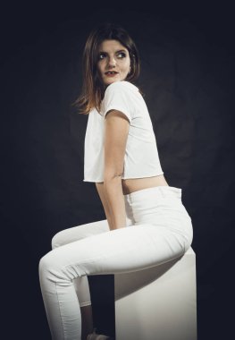 Beyaz kot pantolon ve tişört giymiş güzel bir kadının stüdyo portresi.