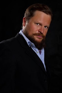 Düşünceli, sakallı, takım elbiseli adam.