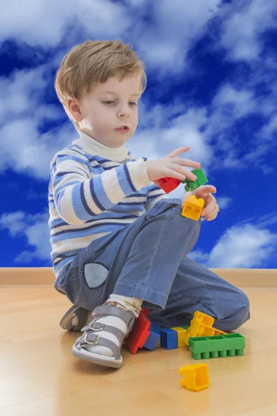男孩玩塑料建筑与云天空背景 — 图库照片