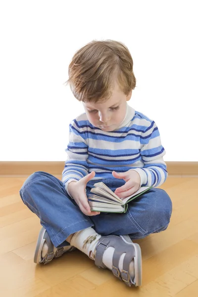 Jongen lezen boek zitplaatsen op de vloer op witte achtergrond — Stockfoto