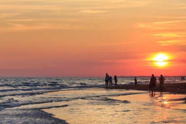 İnsanlar sahilde yürüyor.