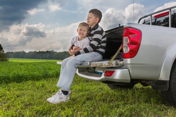 Twee broers siiting op de kofferbak van een auto op natuurlijke achtergrond — Stockfoto