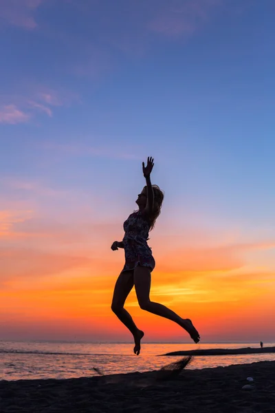 Schöne junge Frau am Strand bei Sonnenuntergang — Stockfoto