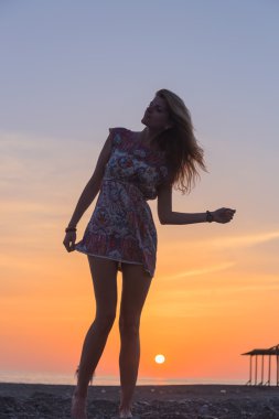 Gün batımında sahilde güzel genç bir kadın.