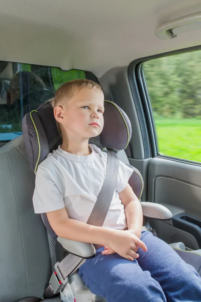 Menino sentado em um carro em cadeira de segurança — Fotografia de Stock