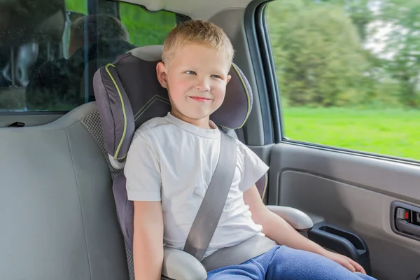 Jongen in een auto in veiligheid stoel zit — Stockfoto