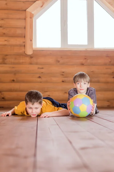 Dois amigos com uma bola deitada no chão — Fotografia de Stock