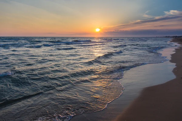 Sunset over beach sea tide sand coast — стоковое фото