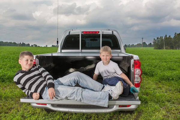 Twee broers siiting op een auto kofferbak — Stockfoto