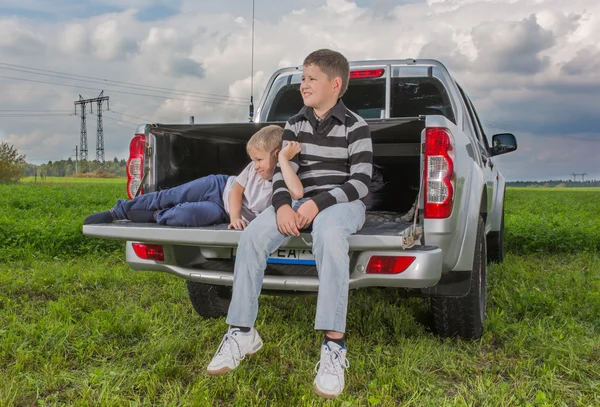 Twee broers siiting op een auto kofferbak — Stockfoto