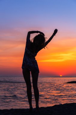 Gün batımında sahilde güzel genç bir kadın.