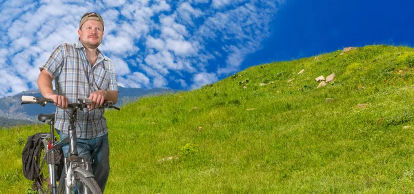 Tourist man standing with a bicycle in a highlands — Stock Photo, Image