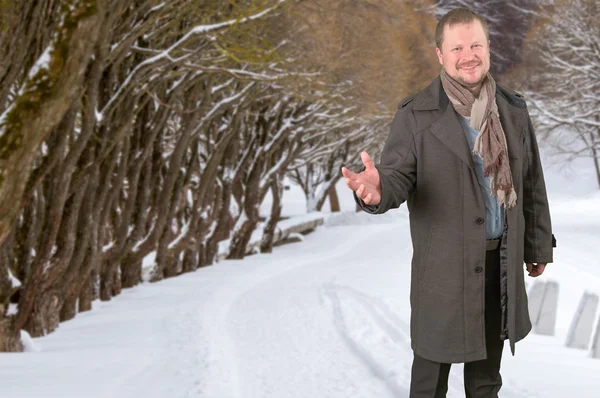 Middle-aged man in a coat looking friendly on winter park background