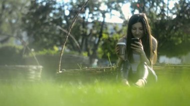 Genç kadın tüketmek kahve ve smartphone cep telefonu ile tarama Internet