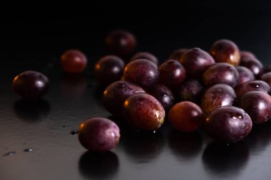 Arka planda bir mum ve siyah bir masa üzerine saçılmış üzümler. . 