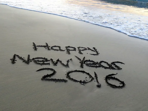 Happy New Year 2016 written in the sand with waves approaching — Stock Photo, Image