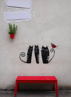 Kırmızı benç siyah kedileri boyuyor kırmızı tencere ve boş tabela ile duvarı boyuyor