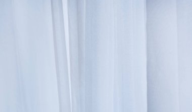 Yumuşak dikey kıvrımlı beyaz tül perdenin soyut arkaplanı. Parlak gün ışığıyla cam kenarında şeffaf kumaş dokusu. Düğün, kaplıca ya da iç mekan için uygun şık kumaşlar..