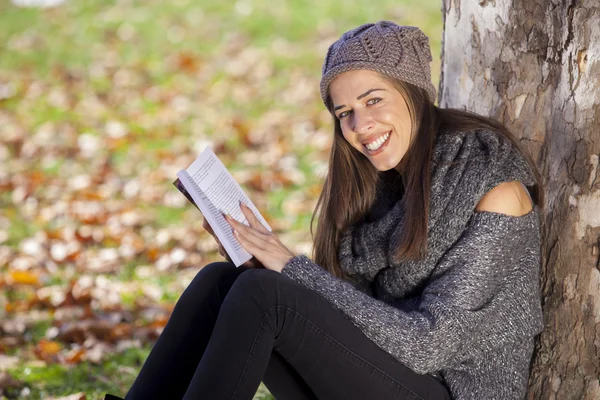 Gadis membaca buku duduk di dekat pohon — Stok Foto