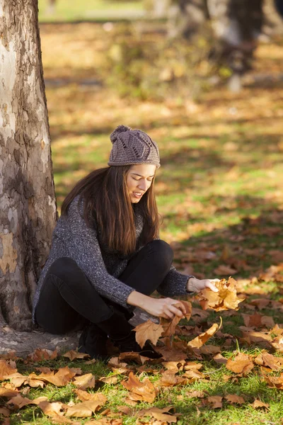 Femme laisse tomber les feuilles dans le parc d'automne — Photo